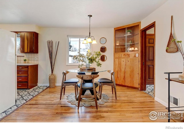 dining space with a notable chandelier and light wood-type flooring