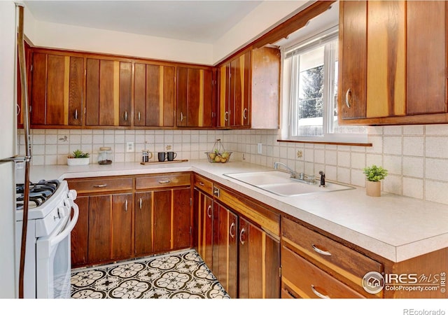 kitchen with decorative backsplash, white range oven, light tile patterned floors, and sink