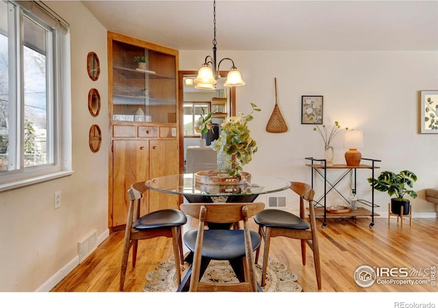 dining space featuring light hardwood / wood-style flooring and a notable chandelier