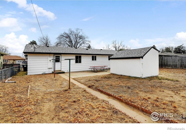 rear view of property featuring a storage unit and a patio area