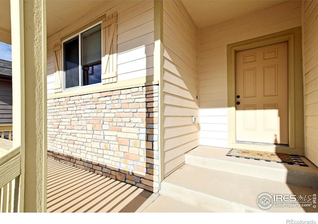 property entrance with covered porch and brick siding