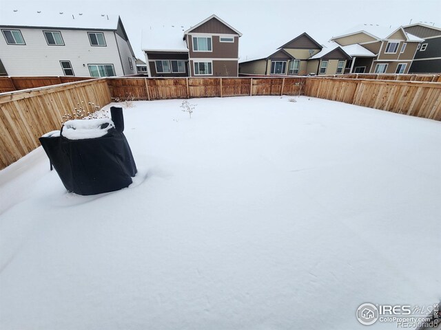 snowy yard with a fenced backyard and a residential view