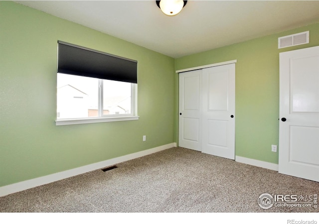 unfurnished bedroom featuring a closet, visible vents, baseboards, and carpet