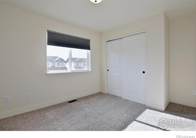 unfurnished bedroom featuring carpet flooring, baseboards, visible vents, and a closet