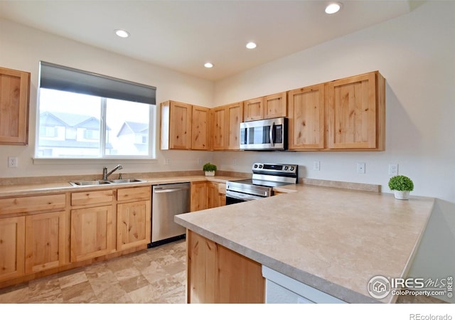 kitchen with light brown cabinets, stainless steel appliances, light countertops, and a sink