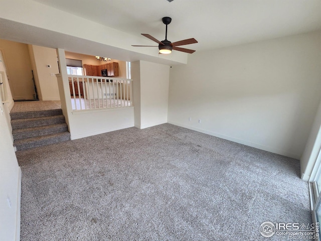 carpeted empty room featuring stairs, baseboards, and ceiling fan