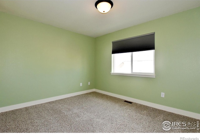 carpeted empty room featuring baseboards and visible vents