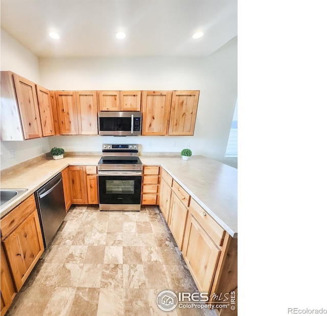 kitchen with a peninsula, light brown cabinets, appliances with stainless steel finishes, and light countertops