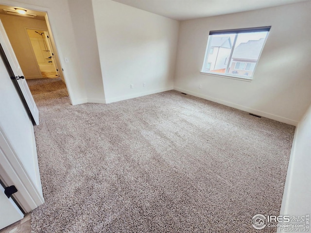 carpeted spare room with visible vents and baseboards