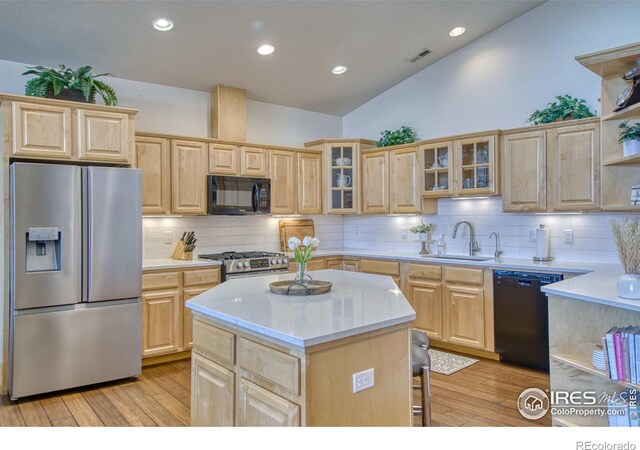 kitchen with light brown cabinetry, sink, a center island, and black appliances