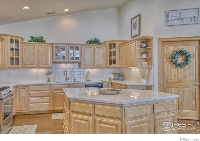 kitchen featuring decorative backsplash, sink, light brown cabinets, a kitchen island, and stainless steel range with gas stovetop