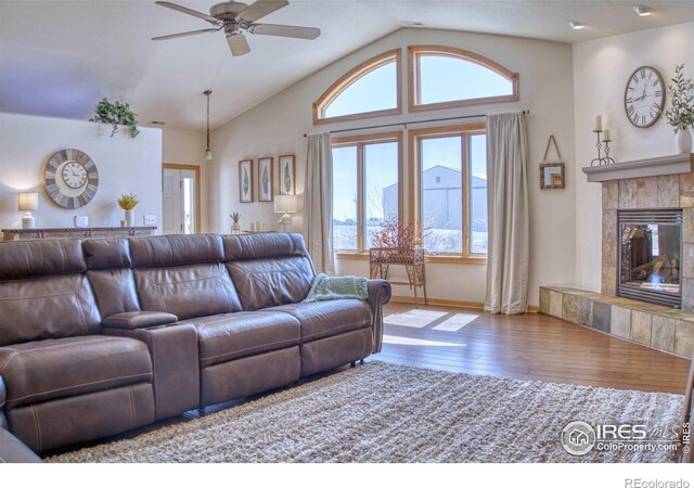 living room featuring ceiling fan, a fireplace, vaulted ceiling, and hardwood / wood-style flooring