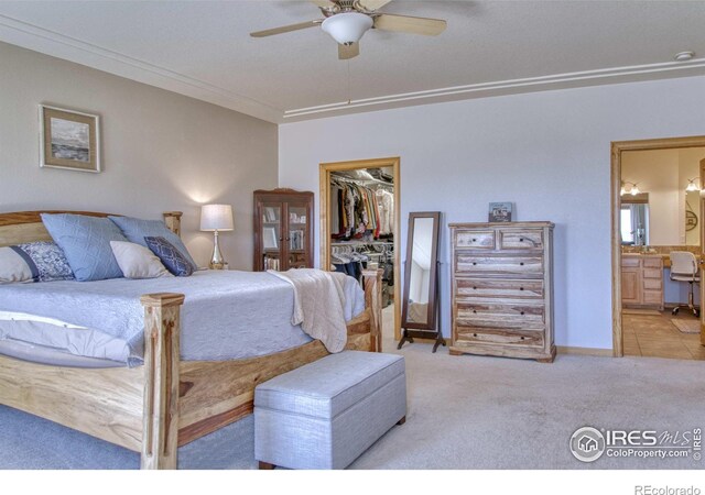 carpeted bedroom featuring ensuite bathroom, ornamental molding, ceiling fan, a spacious closet, and a closet