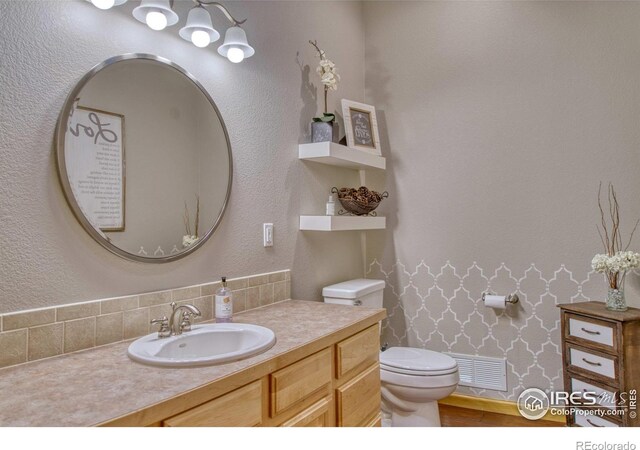 bathroom with vanity, toilet, and backsplash