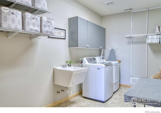 clothes washing area with cabinets, separate washer and dryer, and sink