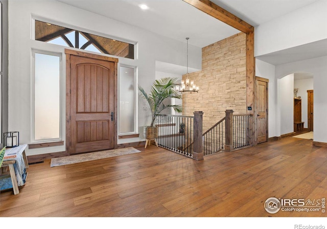 entryway featuring a chandelier, beamed ceiling, wood-type flooring, and high vaulted ceiling