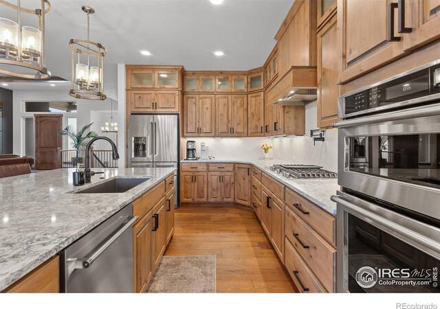 kitchen with sink, light stone countertops, stainless steel appliances, and a chandelier