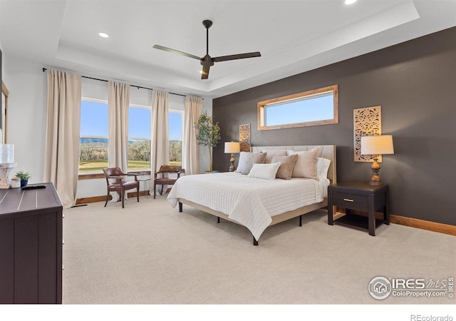 carpeted bedroom featuring ceiling fan and a tray ceiling