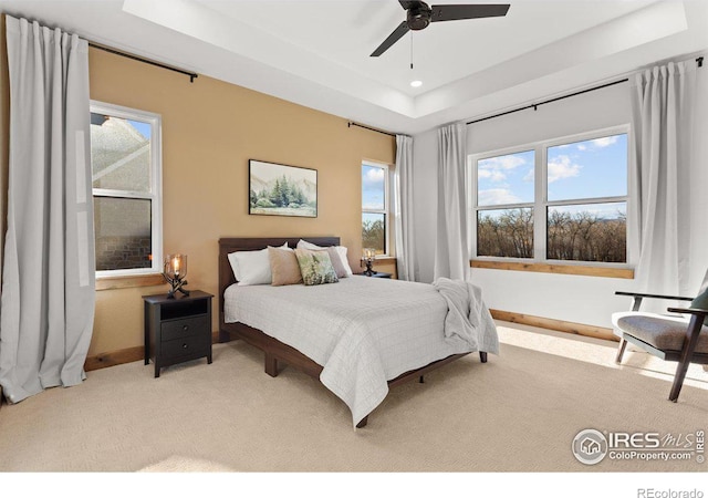 carpeted bedroom featuring a tray ceiling and ceiling fan