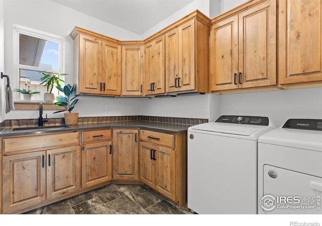 clothes washing area with washer and dryer, cabinets, and sink