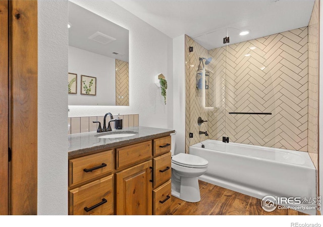 full bathroom with hardwood / wood-style flooring, tiled shower / bath combo, toilet, and vanity