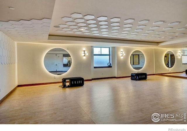 interior space with a raised ceiling, light wood-type flooring, and crown molding