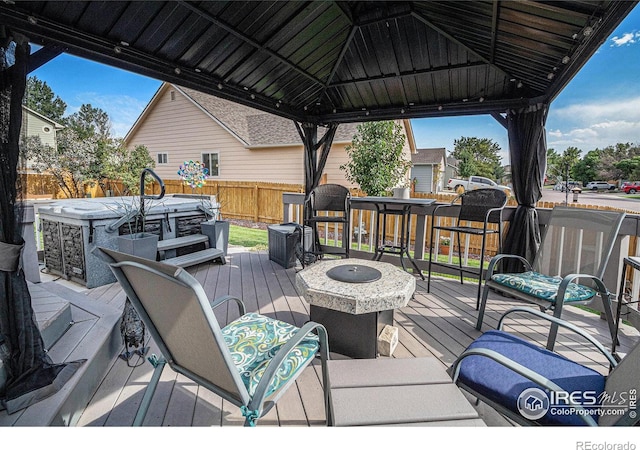 wooden terrace featuring a gazebo, a hot tub, and a fire pit