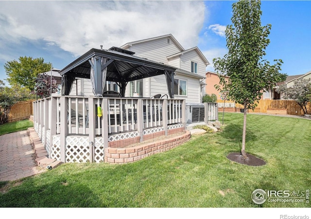 back of house with a gazebo, a deck, and a lawn