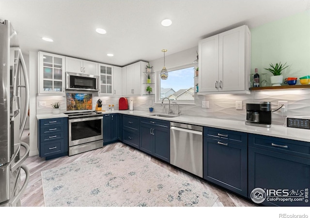 kitchen featuring white cabinets, appliances with stainless steel finishes, blue cabinetry, and sink