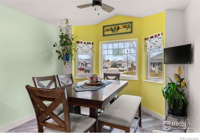 dining space featuring a textured ceiling, ceiling fan, wood-type flooring, and lofted ceiling