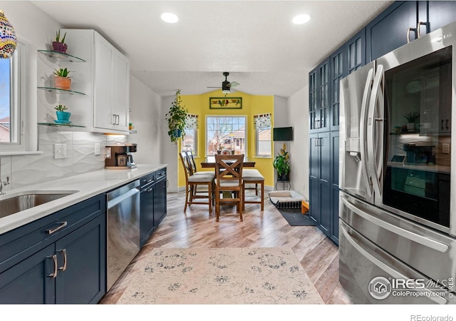 kitchen featuring backsplash, blue cabinets, and appliances with stainless steel finishes