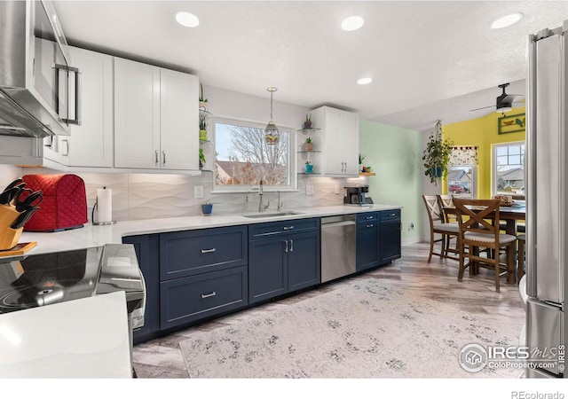 kitchen with white cabinetry, sink, stainless steel appliances, backsplash, and pendant lighting