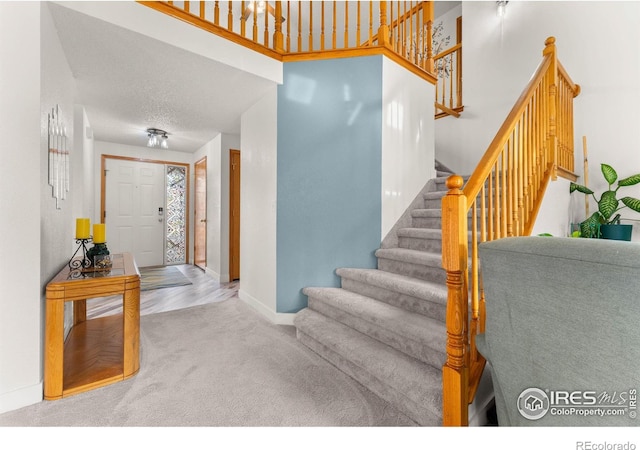 stairway featuring carpet flooring and a textured ceiling