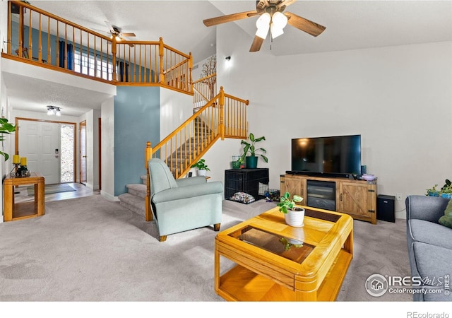 carpeted living room with ceiling fan and high vaulted ceiling