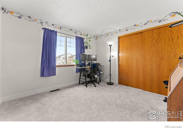 carpeted office with a textured ceiling