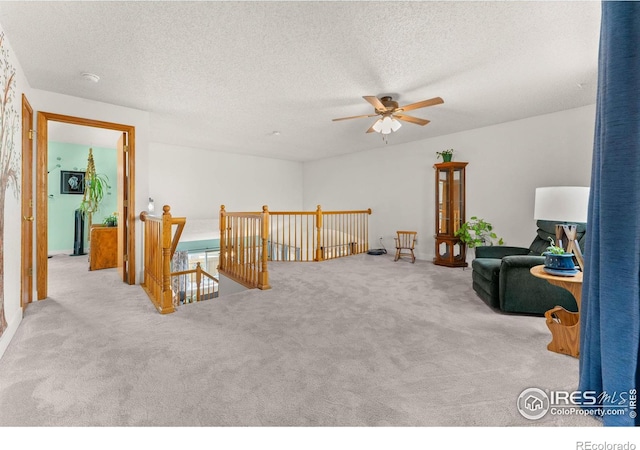 living area featuring ceiling fan, light colored carpet, and a textured ceiling