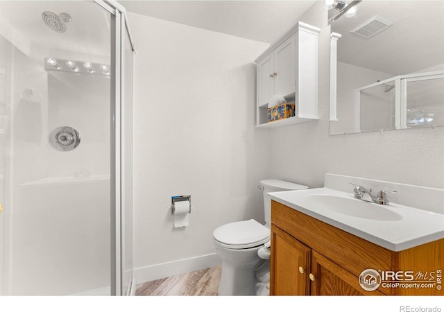 bathroom featuring hardwood / wood-style floors, vanity, toilet, and a shower with shower door