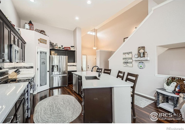 kitchen featuring appliances with stainless steel finishes, sink, backsplash, and an island with sink