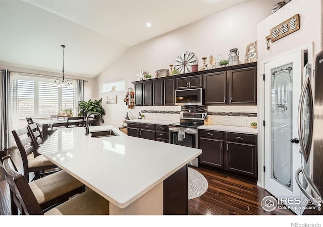 kitchen featuring sink, hanging light fixtures, lofted ceiling, decorative backsplash, and appliances with stainless steel finishes