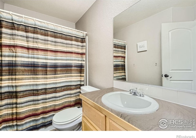 bathroom with vanity, toilet, and a textured ceiling