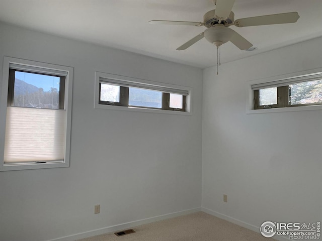 empty room featuring a healthy amount of sunlight, light carpet, and ceiling fan