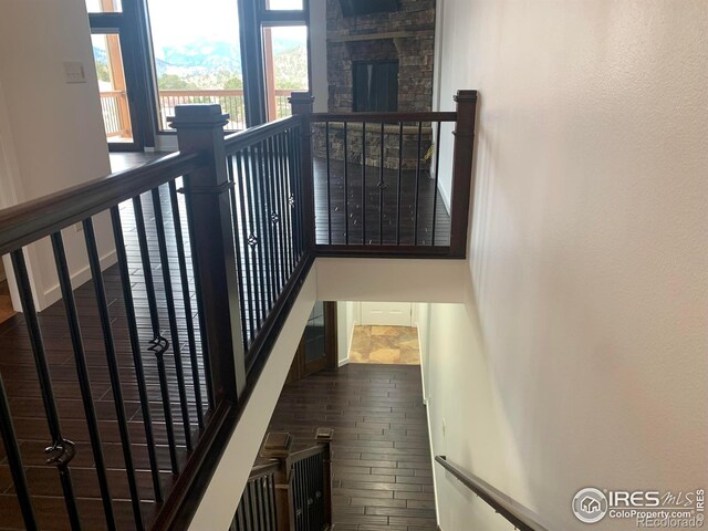 staircase with hardwood / wood-style flooring and a stone fireplace