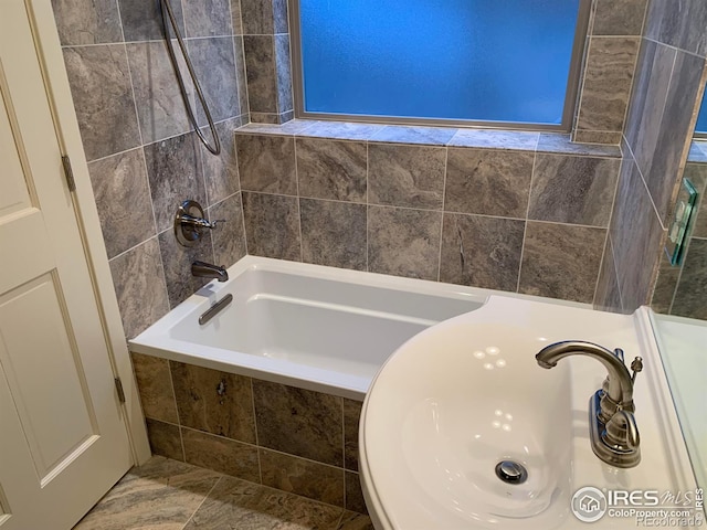 bathroom featuring tiled shower / bath and sink