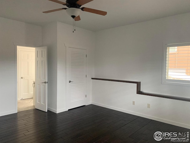 empty room with ceiling fan and dark hardwood / wood-style flooring