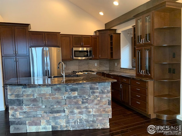 kitchen featuring sink, tasteful backsplash, vaulted ceiling, appliances with stainless steel finishes, and dark stone counters