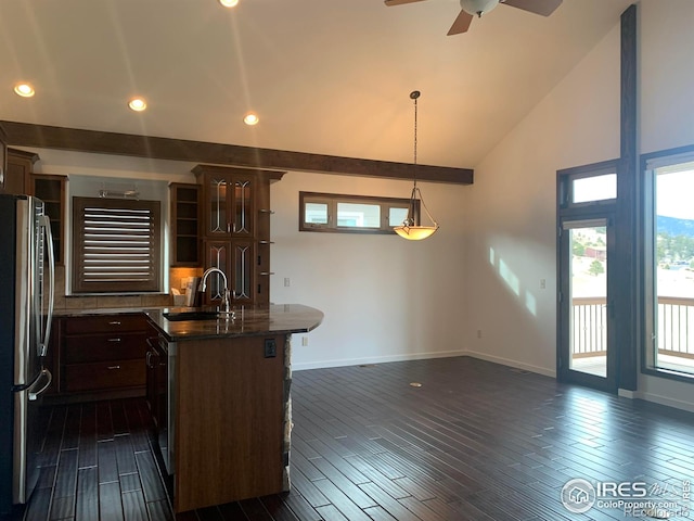 kitchen featuring pendant lighting, an island with sink, sink, stainless steel fridge, and dark wood-type flooring