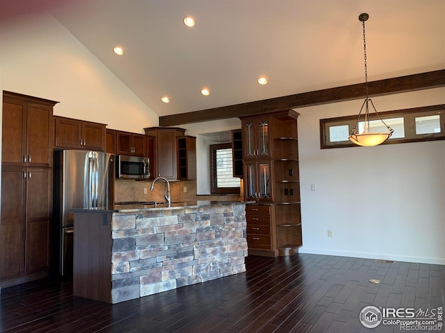 kitchen with dark stone countertops, appliances with stainless steel finishes, dark hardwood / wood-style flooring, pendant lighting, and backsplash