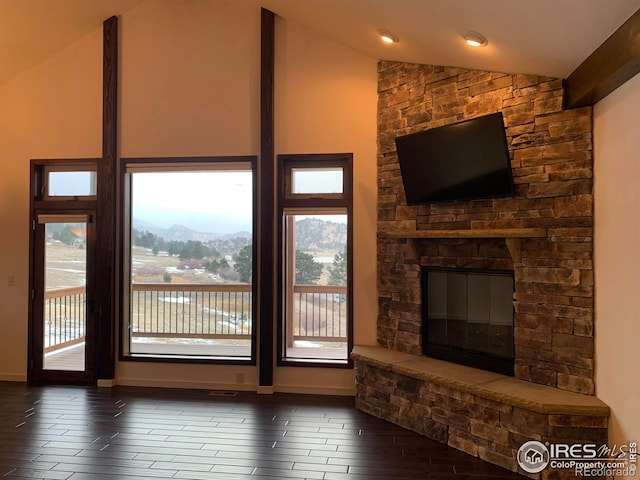 living room featuring lofted ceiling, a stone fireplace, and dark wood-type flooring