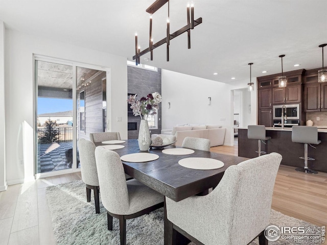 dining room with sink, light hardwood / wood-style floors, and a notable chandelier