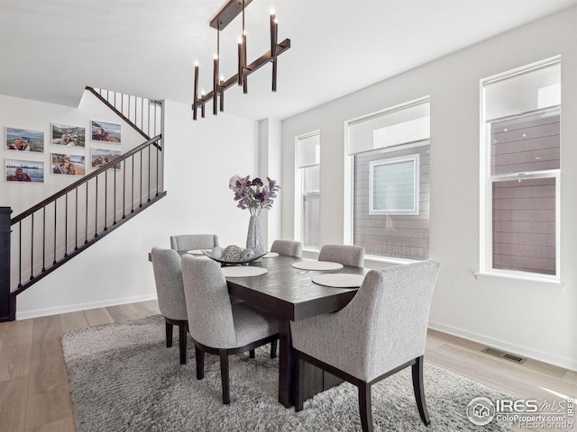 dining space with light hardwood / wood-style flooring and an inviting chandelier